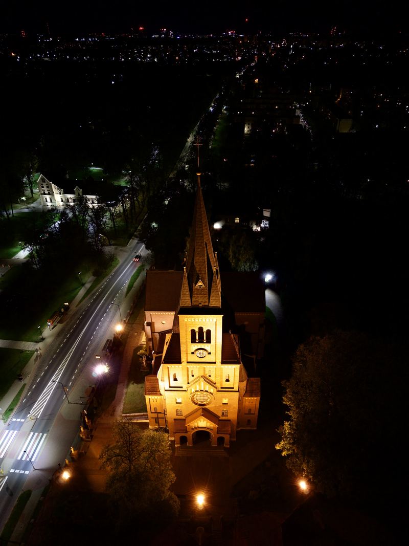 Wieża kościoła nocą, w tle rozświetlona panorama miasta