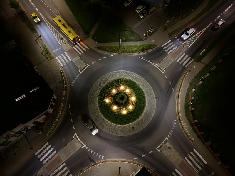 Rondo sfotografowane pionowo z góry nocą, na wlocie żółty autobus
